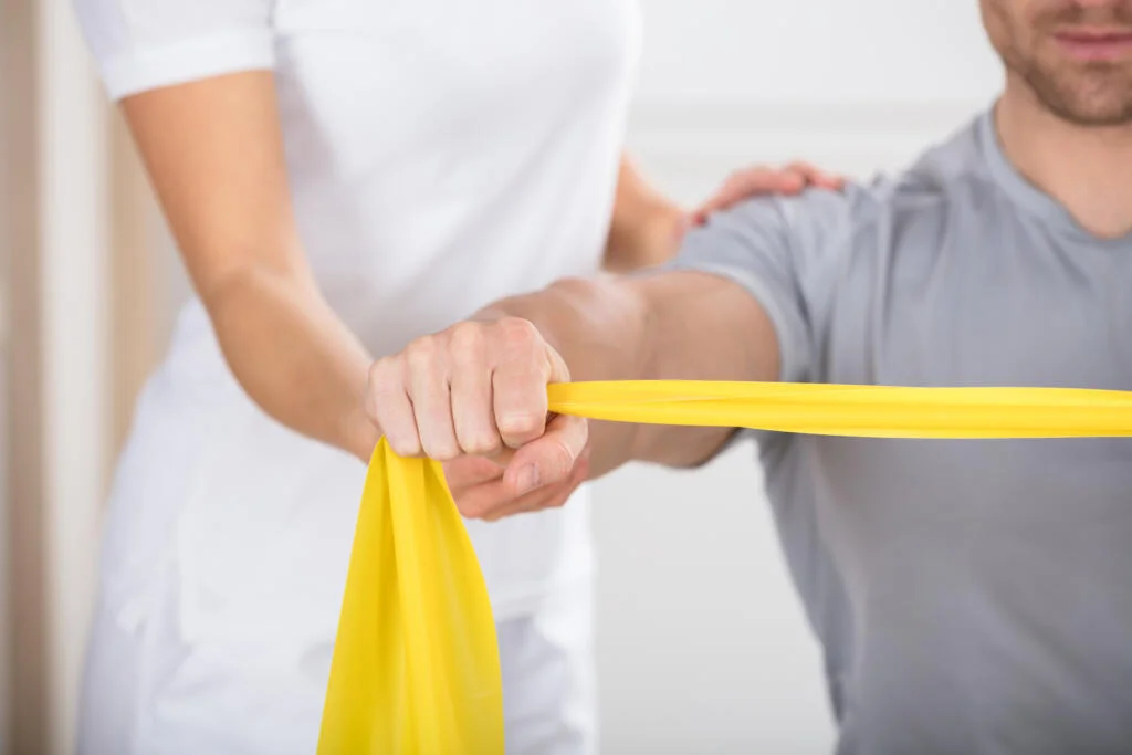 Physiotherapie Solothurn - Close-up Of A Physiotherapist Giving Man A Training With Exercise Band